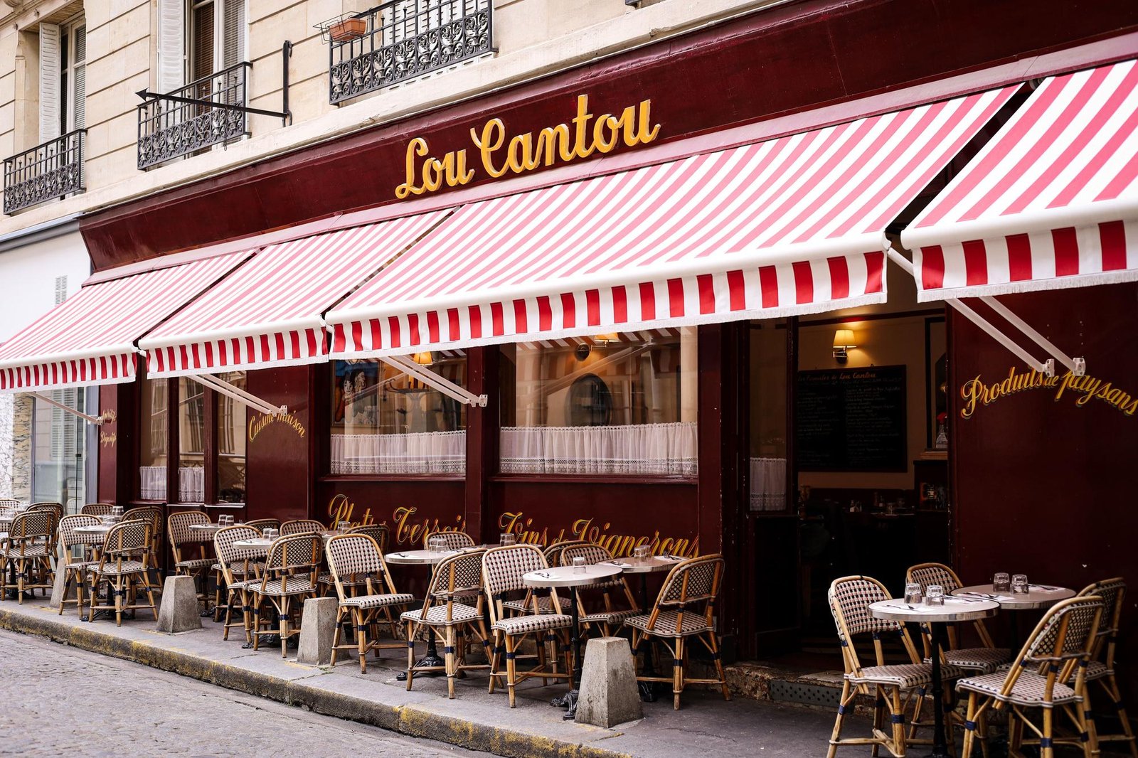La façade bordeaux et le store rayé du Lou Cantou, avec sa terrasse dans la Cité d'Antin