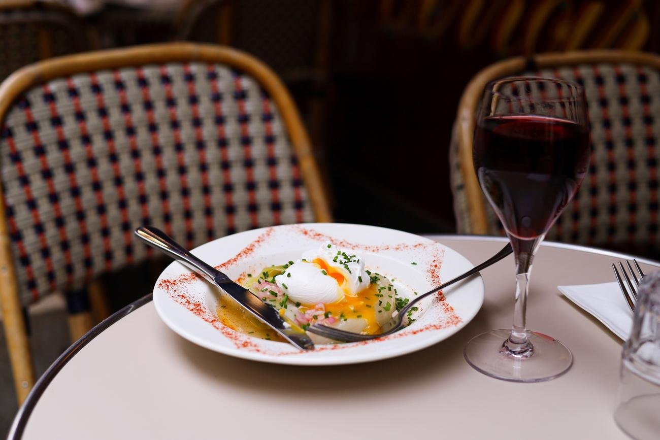 Œuf parfait sur une assiette à liseré rouge, verre de vin rouge